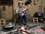 图为正在火塘边弹奏怒族乐器达比亚的郁伍林 张承宗 摄 - 云南频道