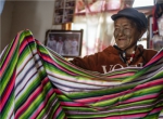 独龙族妇女李文仕在家里展示她亲手织的独龙毯。新华社记者 江文耀 摄 - 云南频道